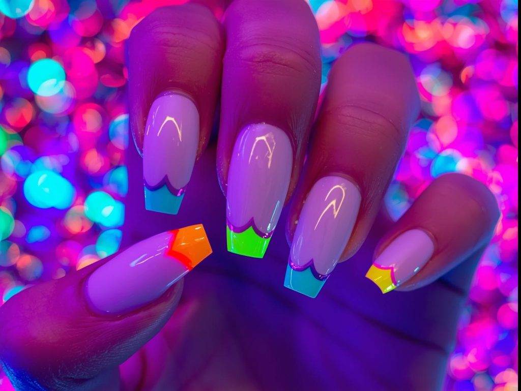Vivid neon rainbow tip nails with bold neon tips.