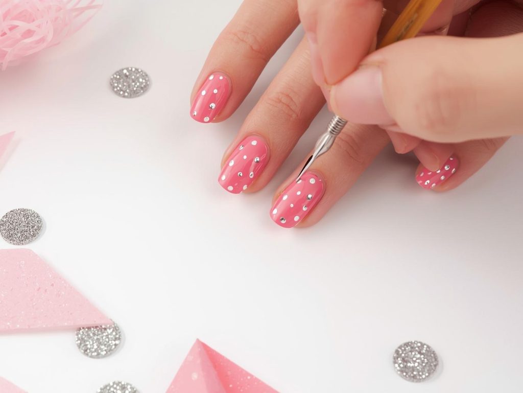 Creating soft pink silver polka dot nail art with silver polka dot patterns.