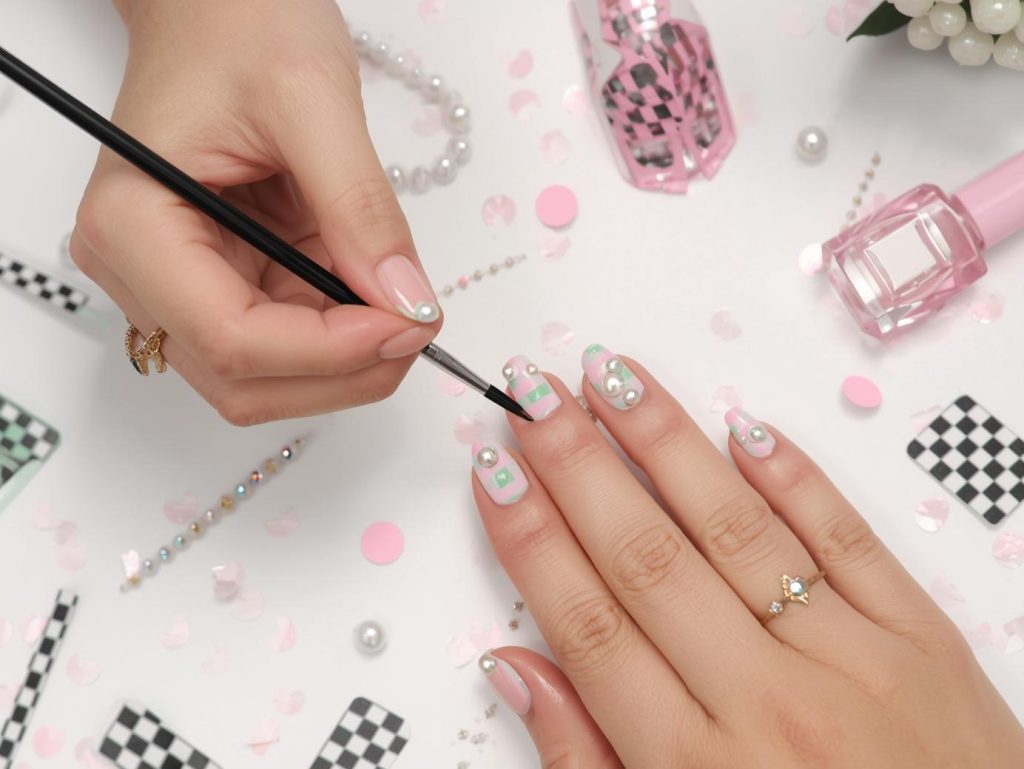 Creating pastel pink and mint green checkerboard nail art with pearl embellishments.