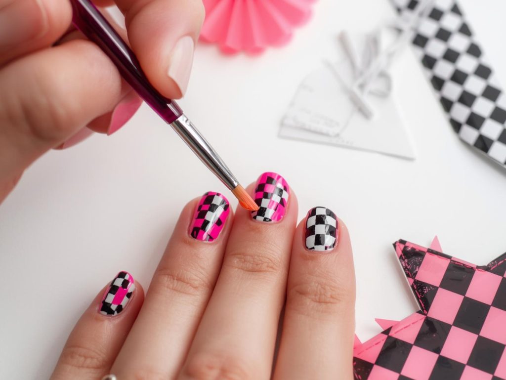 Creating glossy hot pink checkerboard nail art with checkerboard patterns.