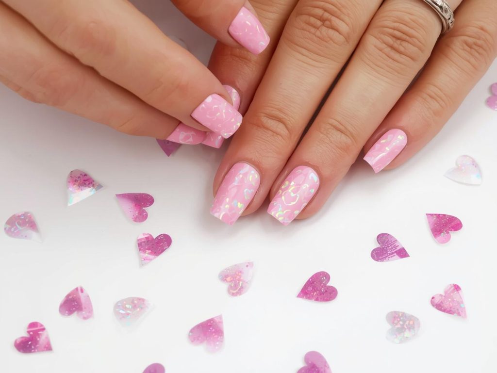 Creating soft pink holographic heart sticker nail art with holographic heart stickers.