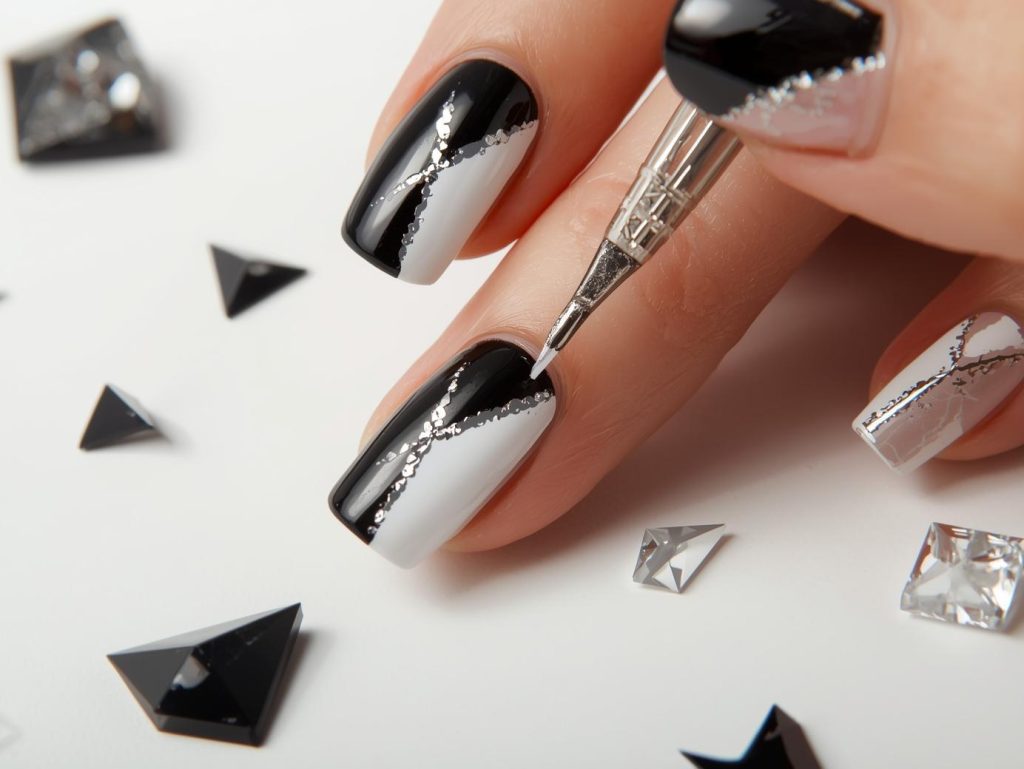 Creating glossy black and white color block nail art with silver accents.