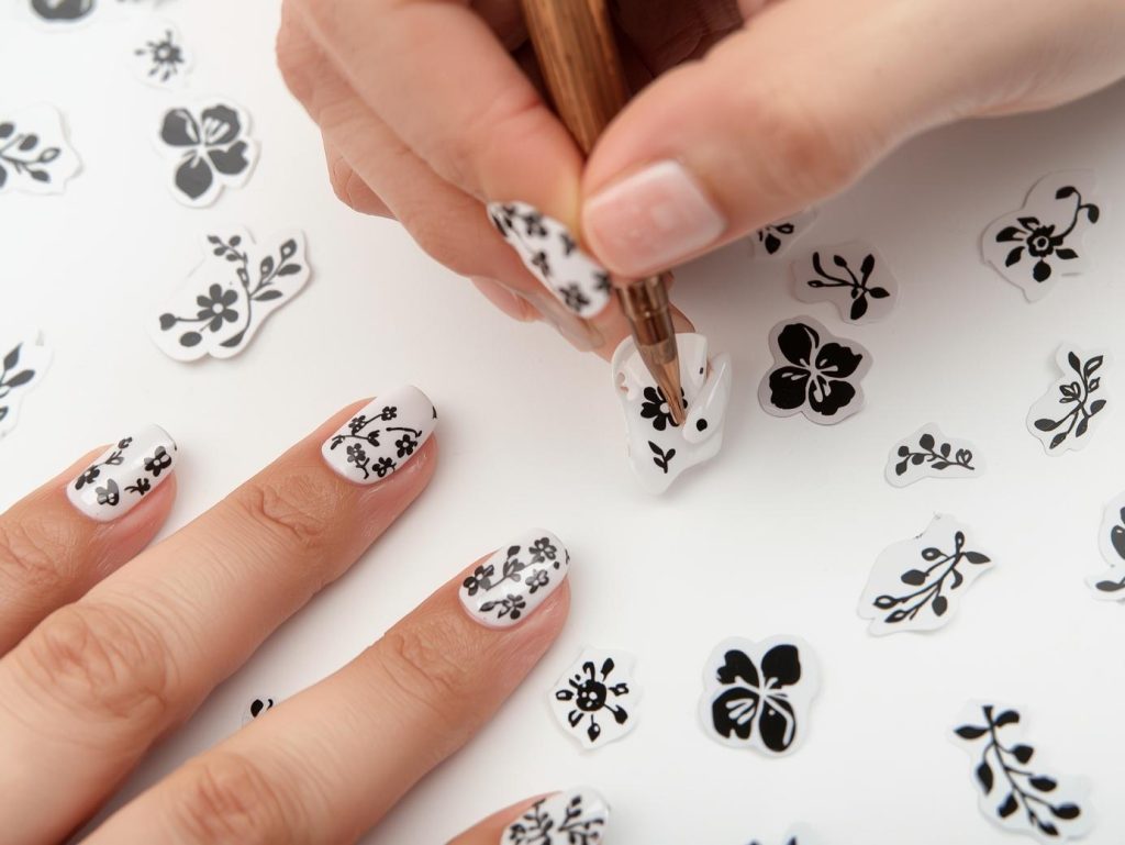 Creating glossy white black floral sticker nail art with black floral stickers.