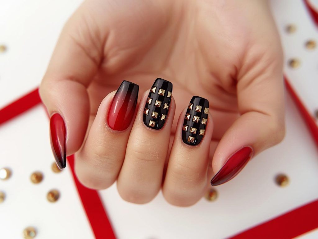 Creating vibrant red ombre nail art with gold stud embellishments.