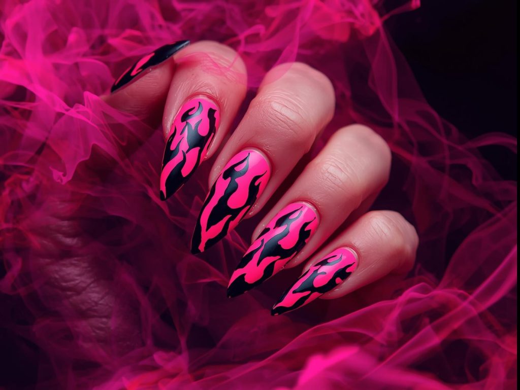 Bold neon pink geometric flame nail art with black patterns.