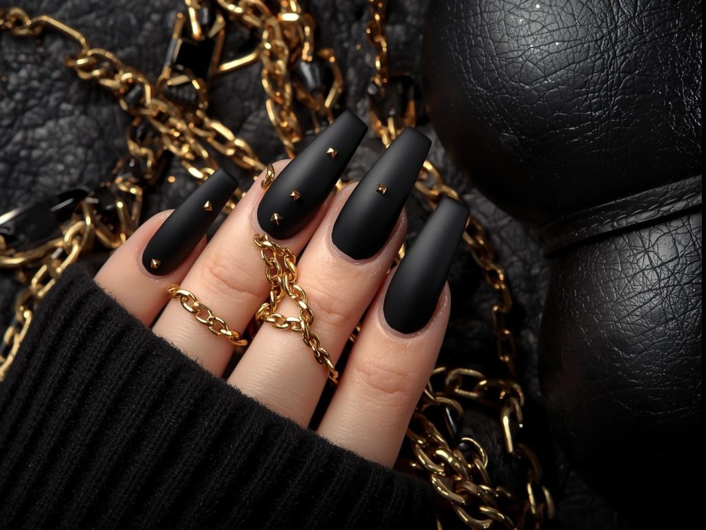 Matte black gold stud nail art with tiny gold embellishments.