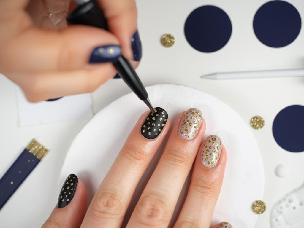 Creating matte navy gold polka dot nail art with gold polka dot patterns.