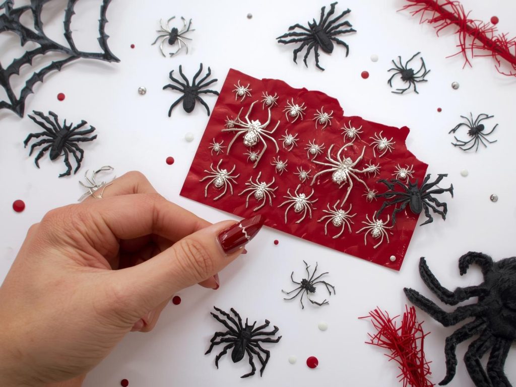 Applying blood red silver spider Halloween nail stickers with silver designs.