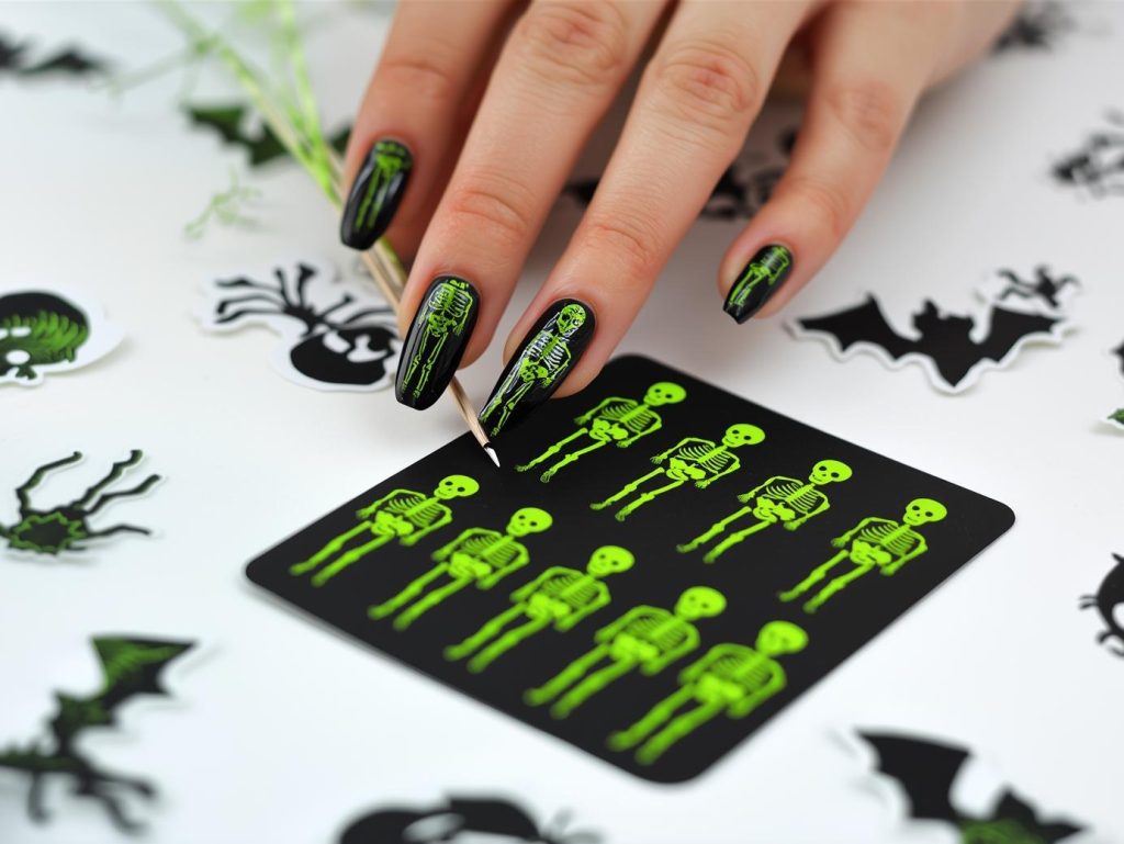  Applying glossy black skeleton Halloween nail stickers with neon green designs.