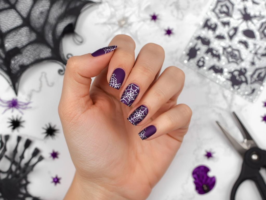 Matte purple silver cobweb Halloween nail art with silver patterns.