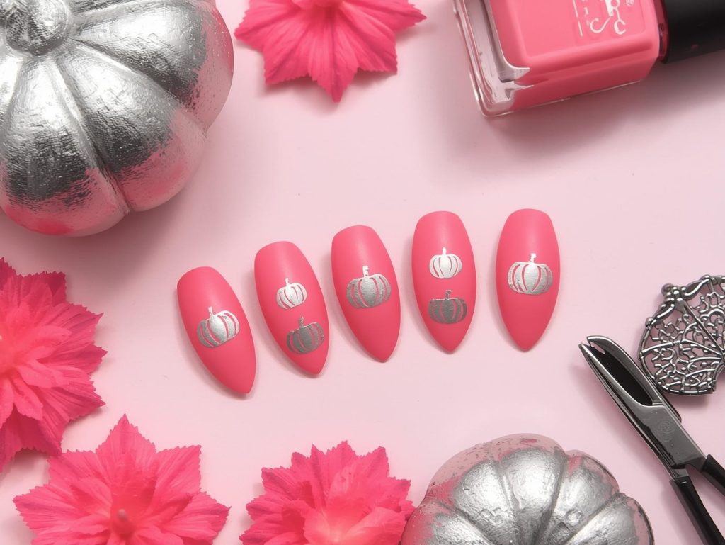 Matte bubblegum pink pumpkin decal pink Halloween nail design with silver decals.