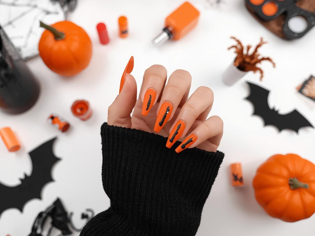 Applying matte blood orange Halloween nail color with black drip accents.