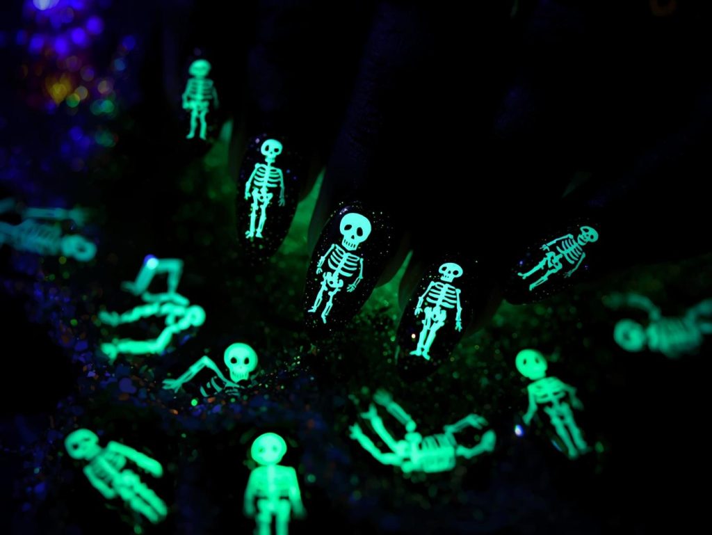 Black glitter skeleton black Halloween nail design with glow-in-the-dark accents.