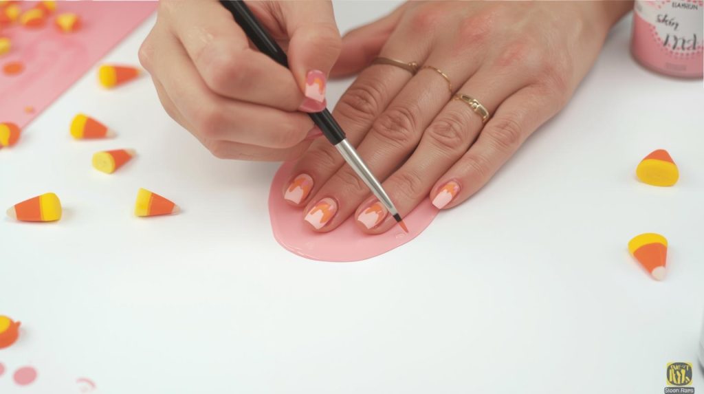 Cute Halloween Nails: Adorable and Pinterest-Worthy Manicures to Adore 10 Applying soft pink candy corn cute Halloween nail design with candy corn patterns.