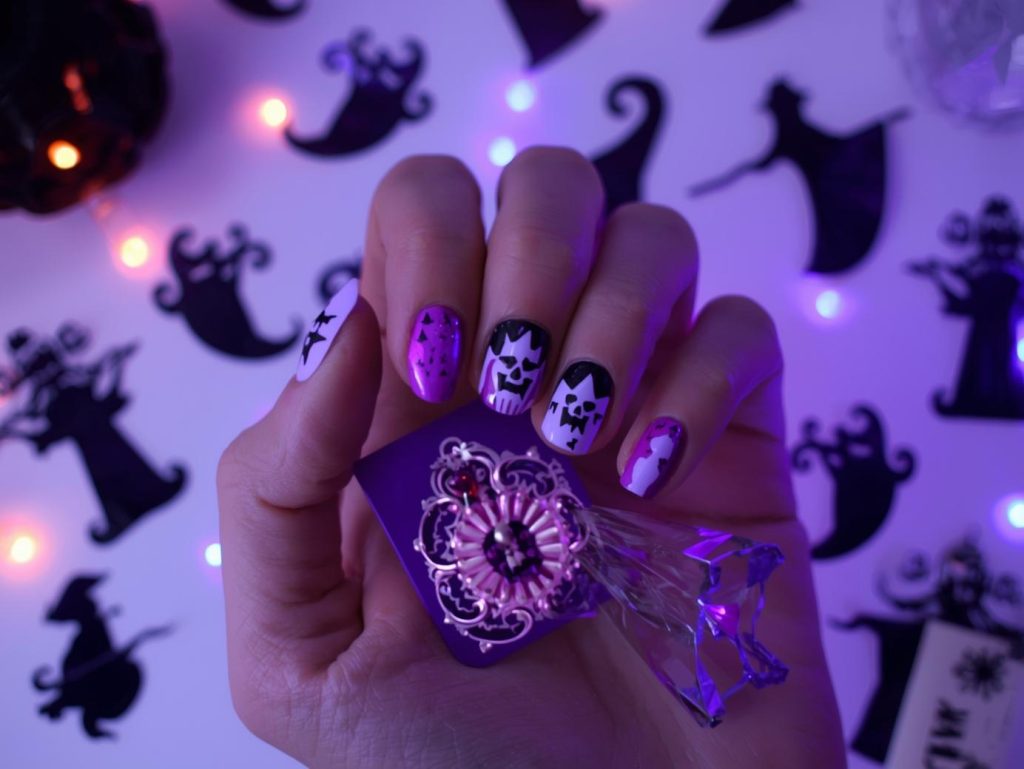 Applying deep purple glow-in-the-dark witch Halloween nail stickers with witch designs